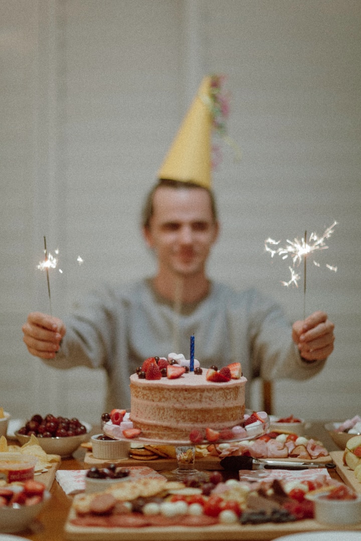 selective focus photography of man holding sparklers between cake